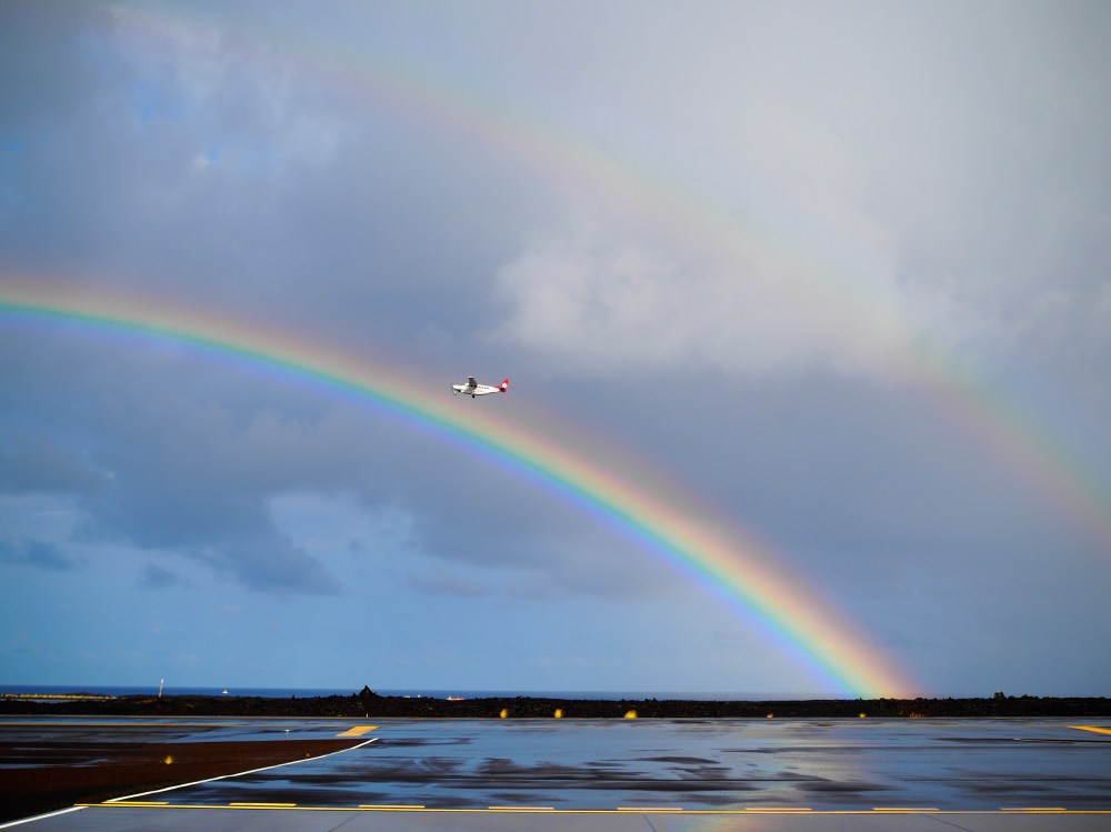 Interisland aircraft flying between two rainbows